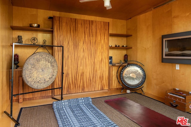 interior space featuring ceiling fan and wood walls