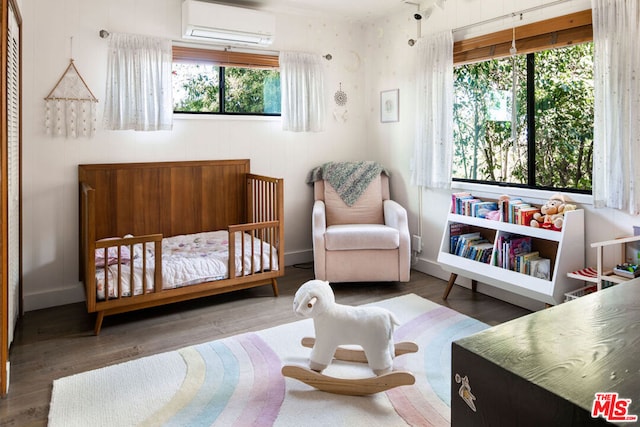 bedroom featuring an AC wall unit, multiple windows, and a crib