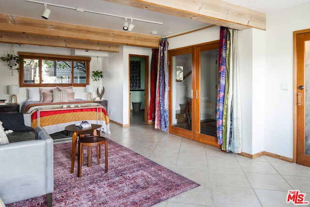 bedroom with rail lighting, beam ceiling, and french doors