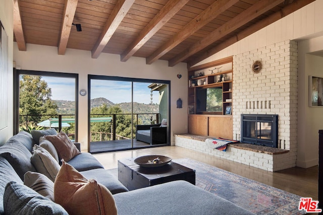 living room featuring hardwood / wood-style flooring, a mountain view, a brick fireplace, wooden ceiling, and beam ceiling