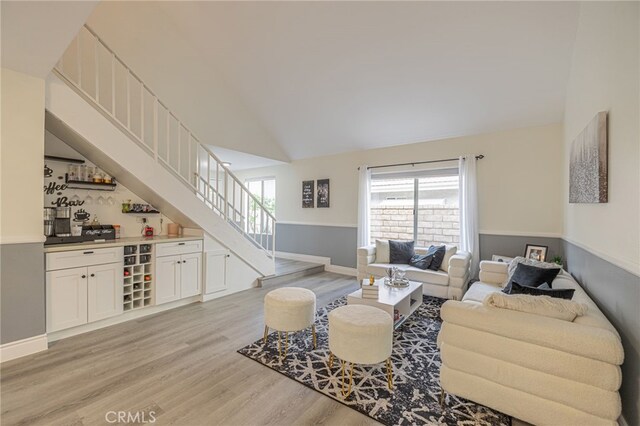 living room featuring bar, high vaulted ceiling, and light wood-type flooring