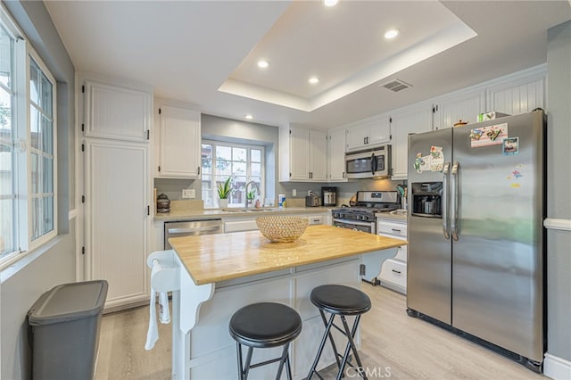 kitchen featuring sink, white cabinetry, stainless steel appliances, and a tray ceiling