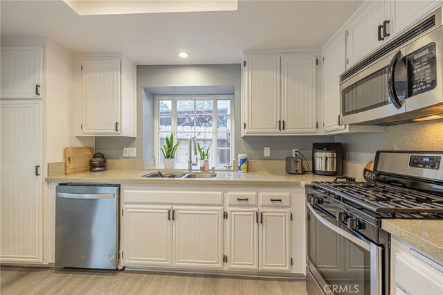 kitchen with white cabinetry, light hardwood / wood-style flooring, stainless steel appliances, and sink