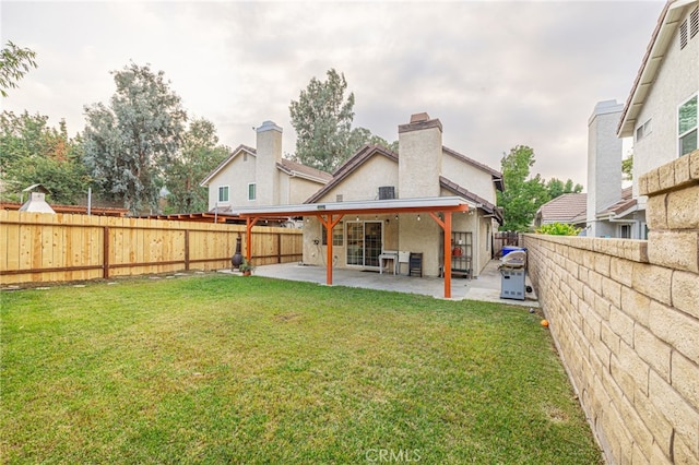 rear view of house with a patio and a lawn