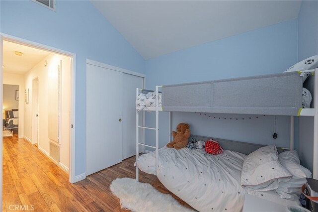 bedroom with light hardwood / wood-style floors, a closet, and vaulted ceiling