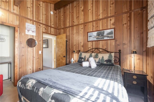 bedroom with a towering ceiling, beam ceiling, wooden walls, and carpet