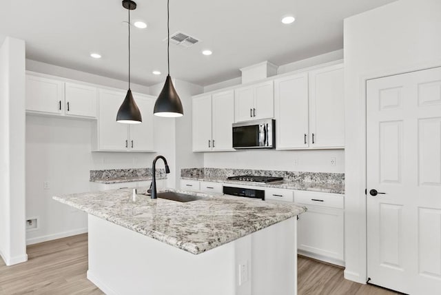 kitchen featuring decorative light fixtures, sink, a center island with sink, and stainless steel appliances