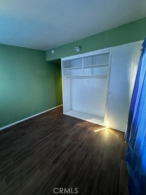 unfurnished bedroom with dark wood-type flooring and a closet