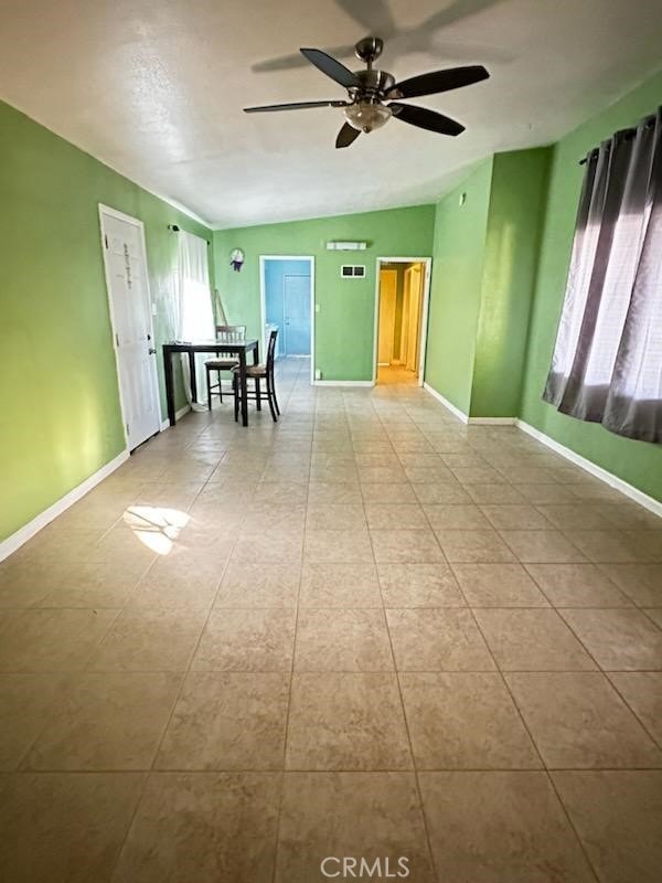 tiled empty room with ceiling fan and vaulted ceiling