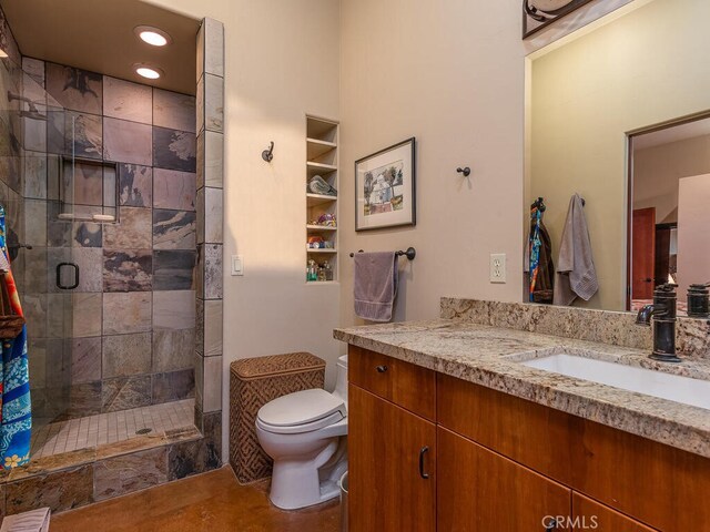 bathroom featuring a shower with door, vanity, toilet, and tile patterned floors