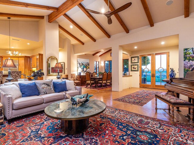 tiled living room featuring french doors, beam ceiling, high vaulted ceiling, and ceiling fan with notable chandelier