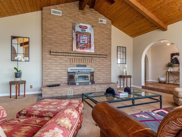 living room with beamed ceiling, carpet floors, a wood stove, and wooden ceiling