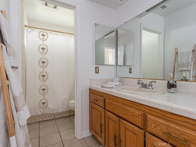 bathroom with toilet, vanity, a shower with shower curtain, and tile patterned flooring