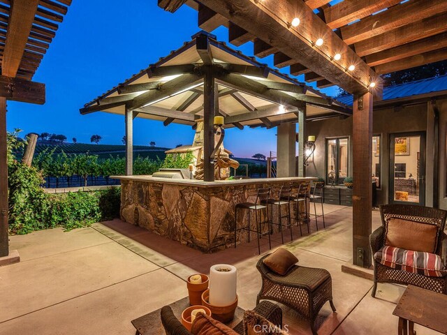 patio terrace at dusk with a bar and a pergola