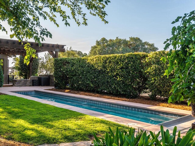 view of swimming pool with a pergola and a lawn