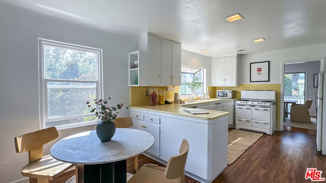 kitchen featuring white appliances, tasteful backsplash, kitchen peninsula, white cabinets, and dark wood-type flooring