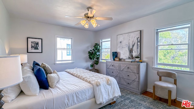 bedroom with hardwood / wood-style floors, multiple windows, and ceiling fan