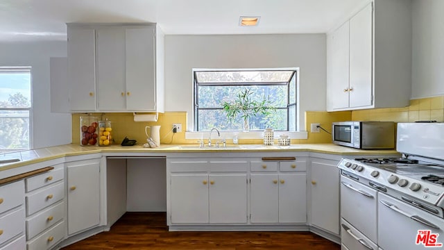 kitchen with a wealth of natural light, decorative backsplash, white cabinetry, and dark hardwood / wood-style floors