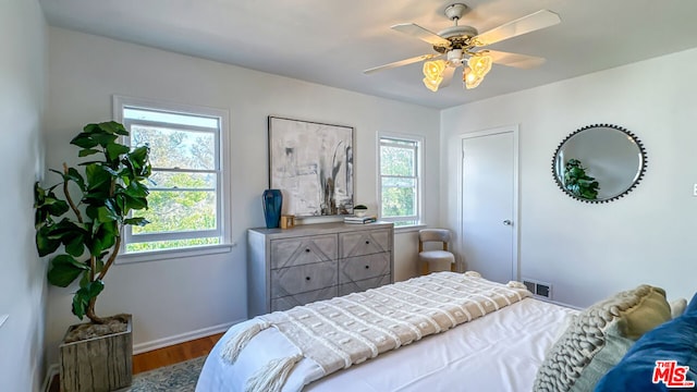 bedroom featuring multiple windows, wood-type flooring, and ceiling fan