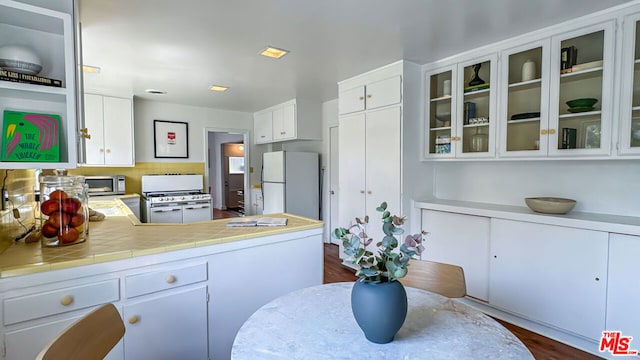 kitchen with white appliances, dark hardwood / wood-style floors, and white cabinets