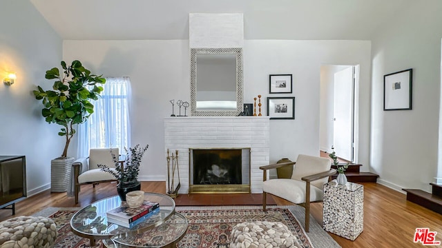 living room with wood-type flooring and a brick fireplace