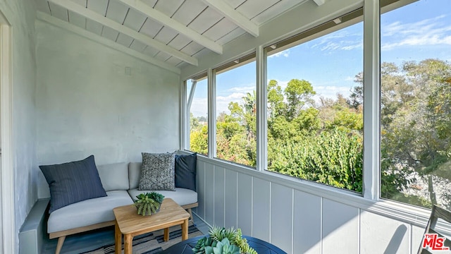 sunroom / solarium featuring vaulted ceiling with beams