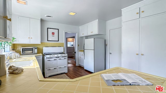 kitchen with tile counters, dark hardwood / wood-style flooring, white cabinets, white appliances, and tasteful backsplash