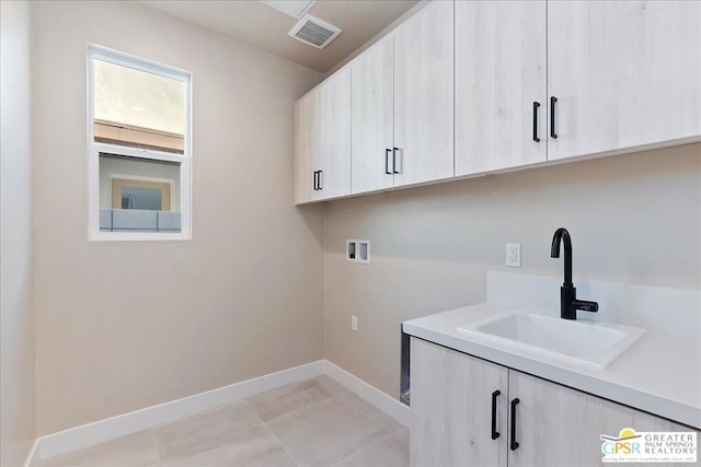 laundry room featuring cabinets, hookup for a washing machine, sink, and light tile patterned flooring