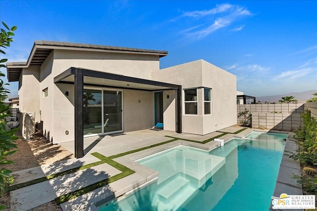 rear view of property with a swimming pool with hot tub and a patio area