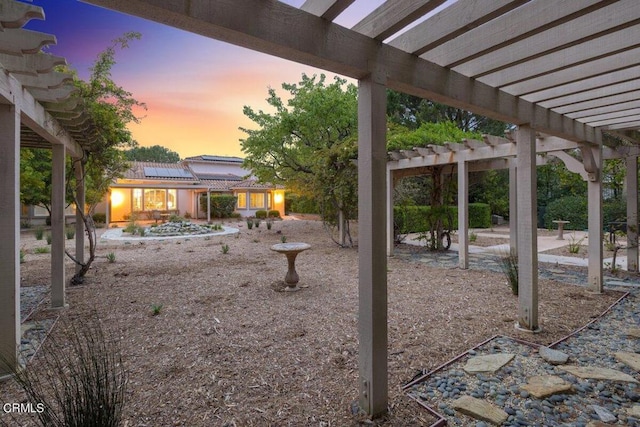 yard at dusk featuring a pergola and a patio