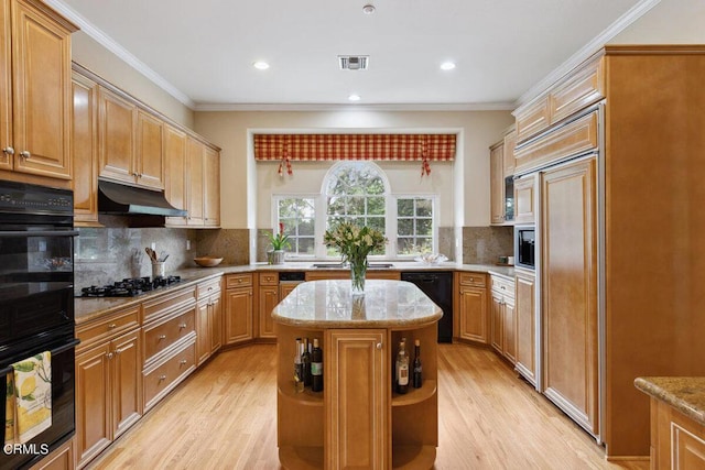 kitchen featuring light stone counters, a center island, light hardwood / wood-style floors, black appliances, and decorative backsplash