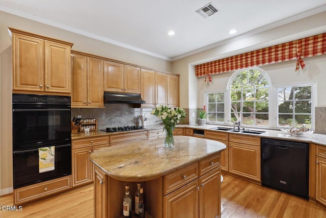 kitchen featuring sink, a center island, light stone counters, light hardwood / wood-style flooring, and black appliances