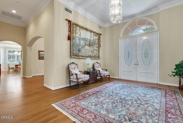 foyer with wood-type flooring, a chandelier, and crown molding