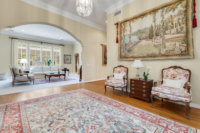 living area with ornamental molding, hardwood / wood-style flooring, and a notable chandelier