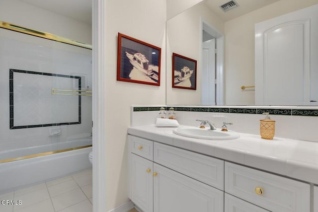 full bathroom with tile patterned flooring, vanity, bath / shower combo with glass door, and toilet