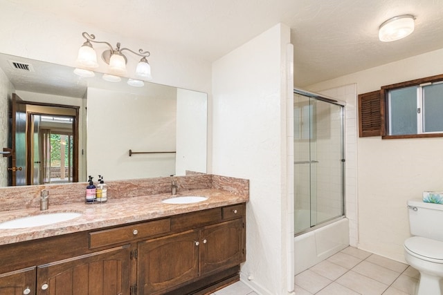 full bathroom with bath / shower combo with glass door, a textured ceiling, vanity, tile patterned flooring, and toilet