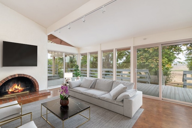 sunroom / solarium featuring plenty of natural light, a fireplace, track lighting, and vaulted ceiling