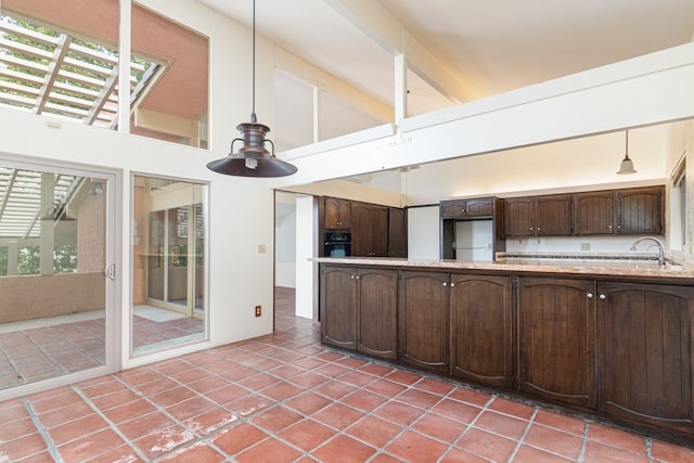 kitchen with dark brown cabinets, high vaulted ceiling, decorative light fixtures, and stainless steel refrigerator