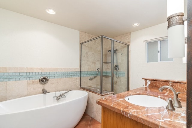 bathroom with plus walk in shower, vanity, tile patterned floors, and tile walls