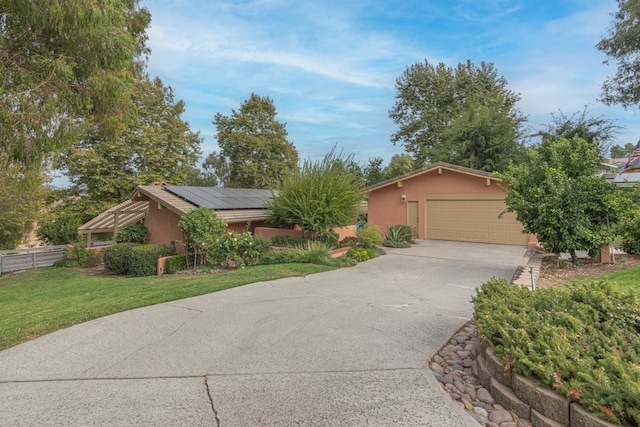 ranch-style home with solar panels, a garage, and a front lawn