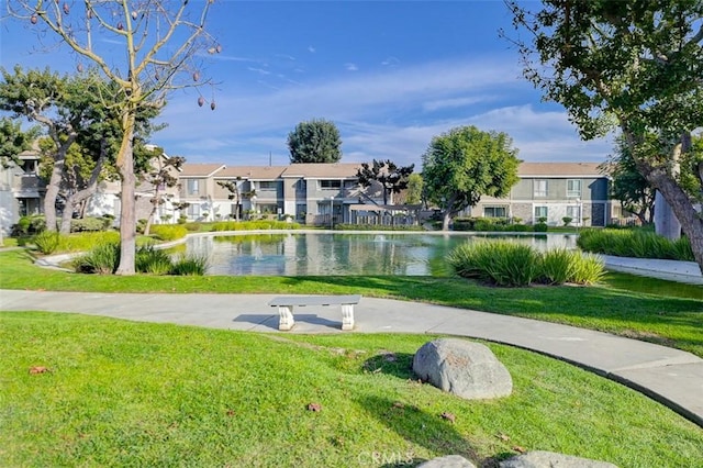 view of property's community with a water view and a lawn