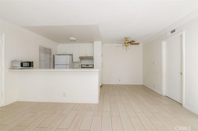 kitchen with white fridge, white cabinetry, kitchen peninsula, stove, and crown molding