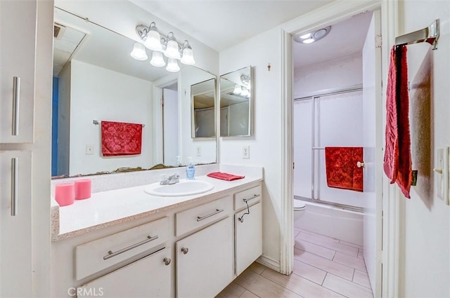 full bathroom with combined bath / shower with glass door, vanity, and toilet