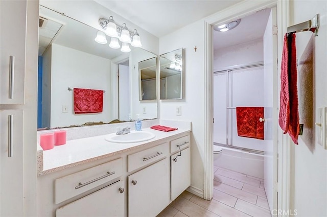 full bathroom with vanity, toilet, and combined bath / shower with glass door