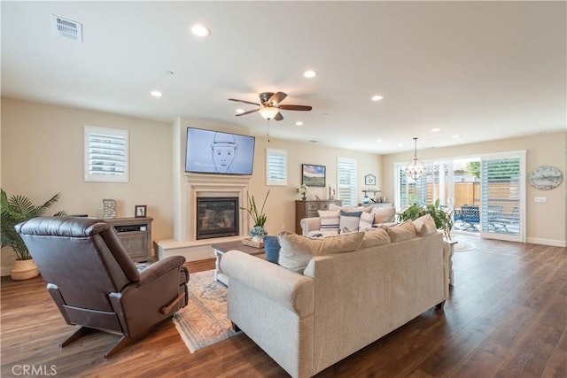 living room with dark hardwood / wood-style flooring and ceiling fan with notable chandelier