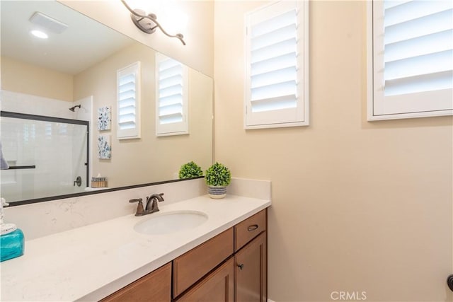 bathroom featuring a shower with door and vanity