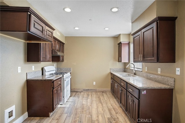 kitchen featuring dark brown cabinetry, white gas stove, and sink