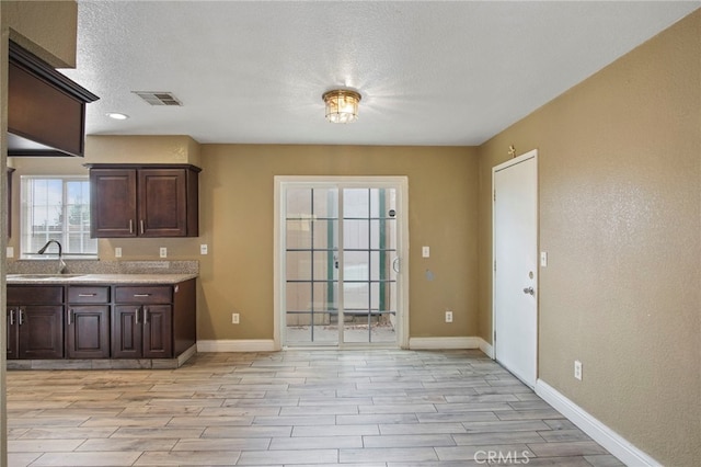 kitchen with dark brown cabinetry, sink, and light hardwood / wood-style floors