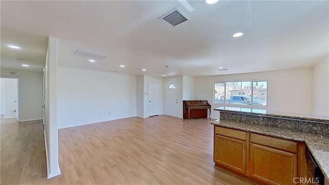 kitchen with light hardwood / wood-style floors and dark stone countertops