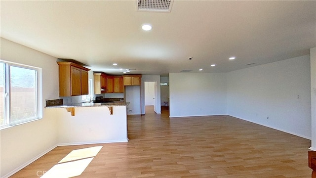 kitchen with light hardwood / wood-style flooring, kitchen peninsula, and a breakfast bar area